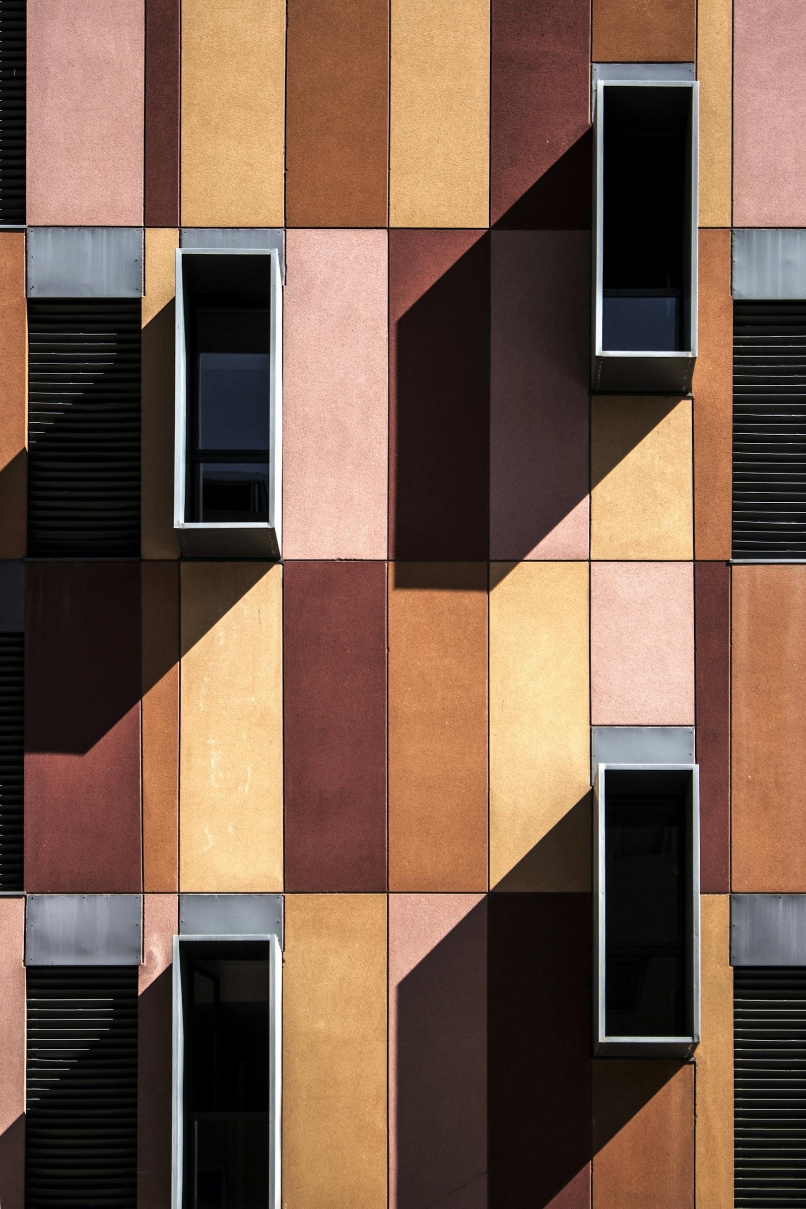 Colorful modern facade with geometric design and shadows highlighting windows.